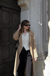 a lady in a white vest, a long trench coat and a pair of black pants